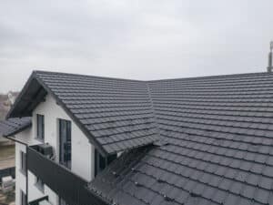 Stunning modern house with a sleek black tiled roof under a cloudy sky