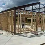 Barndominium construction in progress in East Texas. Three builders are present on the construction field.