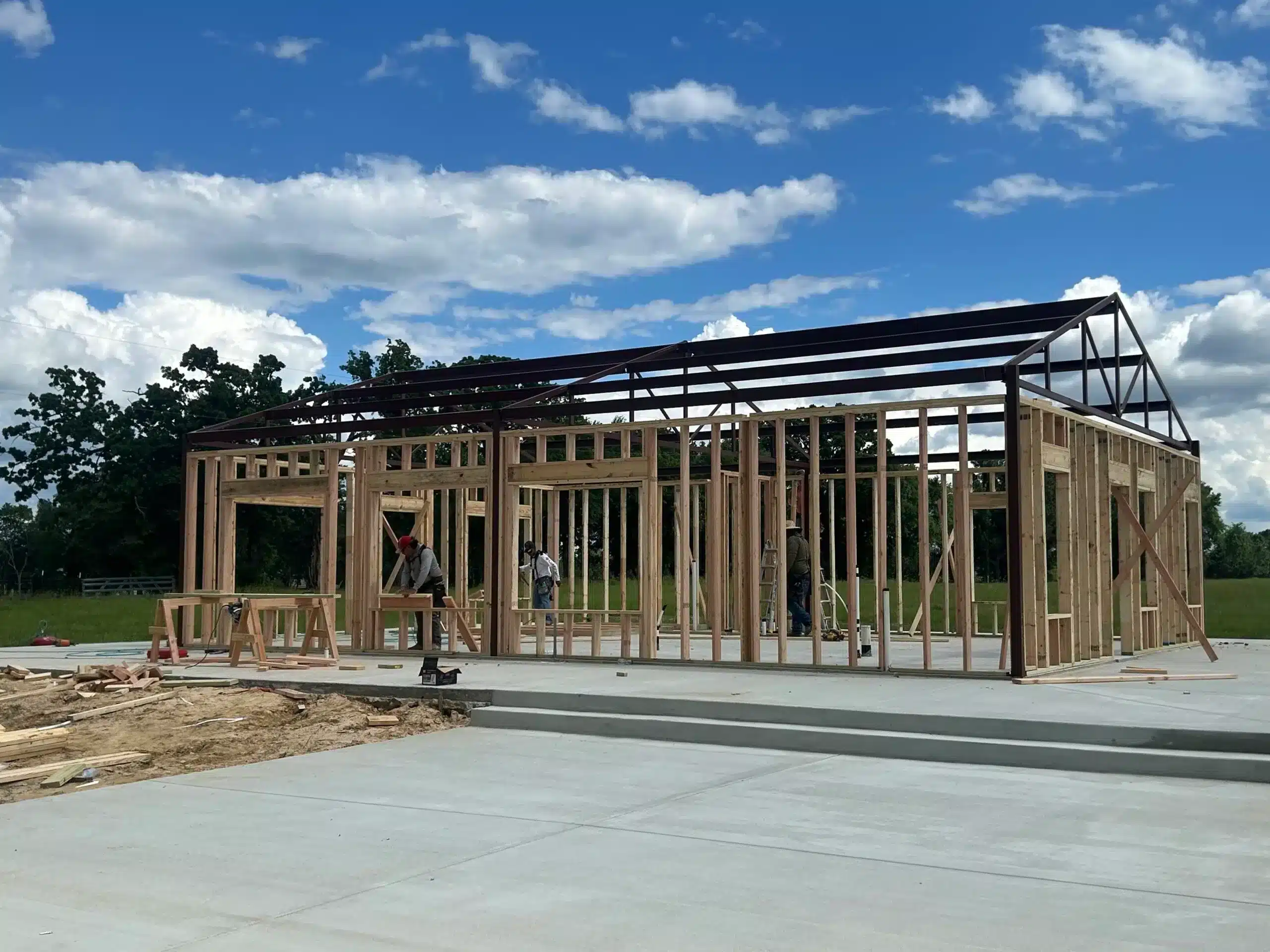 Barndominium framing on a raised concrete pad set above the surrounding grade so water drains away from the slab
